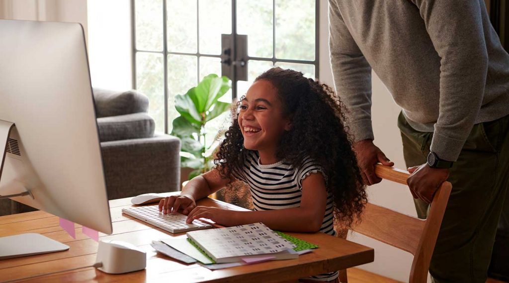 Una niña con un portátil conectada a la red inalámbrica y estudiando desde casa.